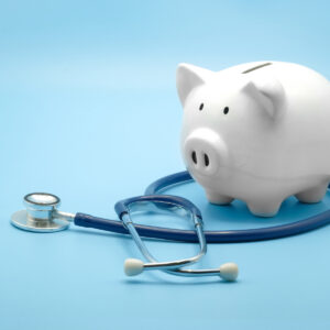 Piggy bank with stethoscope isolated on light blue background with copy space. Health care financial checkup or saving for medical insurance costs concept.